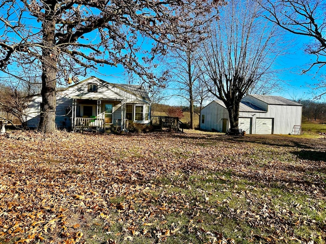 back of property with covered porch, a garage, and an outdoor structure