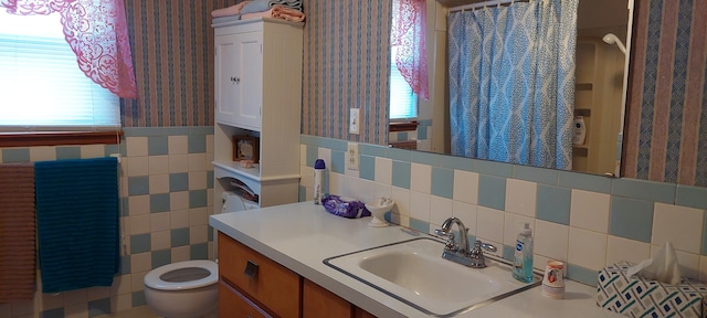 bathroom with toilet, vanity, and tile walls