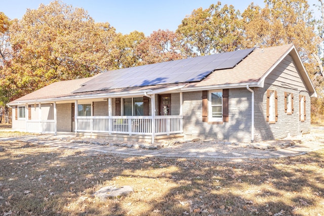 single story home featuring solar panels and covered porch