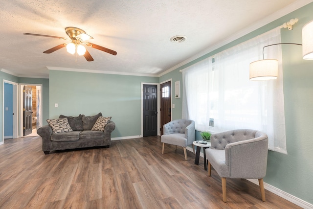 living room with a textured ceiling, hardwood / wood-style flooring, ceiling fan, and crown molding