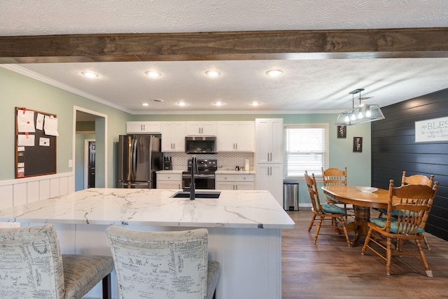 kitchen with sink, dark hardwood / wood-style floors, light stone countertops, white cabinetry, and appliances with stainless steel finishes