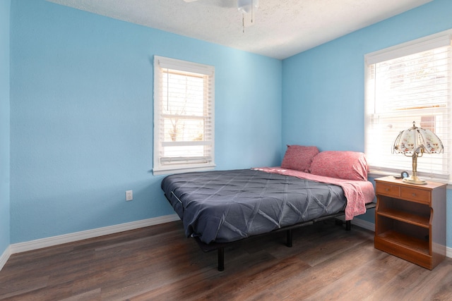 bedroom with dark wood-type flooring, a textured ceiling, and ceiling fan