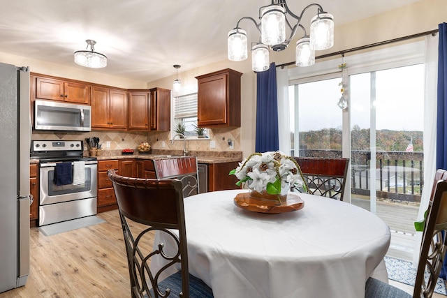 218 Windridge Rd, Branson, MO 65616 - kitchen with stainless steel appliances, a chandelier, decorative backsplash, and plenty of natural light