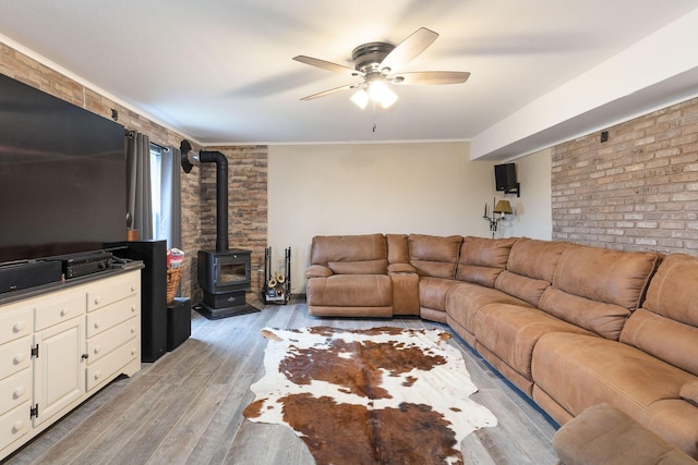 218 Windridge Rd, Branson, MO 65616 - living room with a wood stove, ceiling fan, light wood-type flooring, ornamental molding, and brick wall