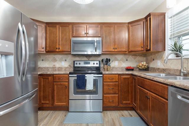 218 Windridge Rd, Branson, MO 65616 - kitchen with appliances with stainless steel finishes, a sink, light wood-type flooring, brown cabinetry, and tasteful backsplash