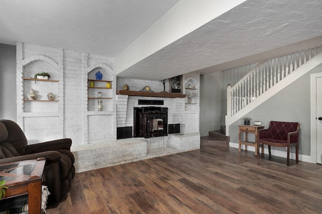 living room with a fireplace, a textured ceiling, built in shelves, and dark hardwood / wood-style flooring