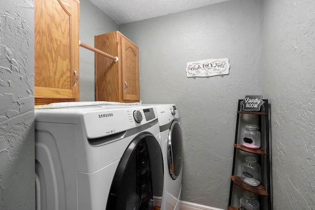 clothes washing area with washer and clothes dryer, cabinets, and a textured ceiling