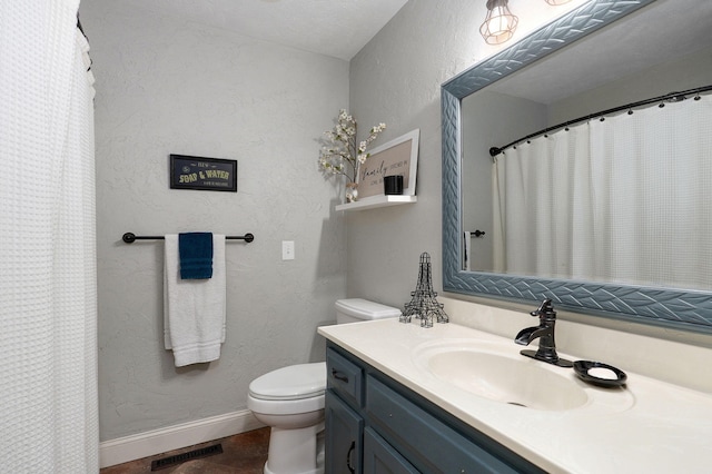 bathroom with toilet, vanity, and a textured ceiling