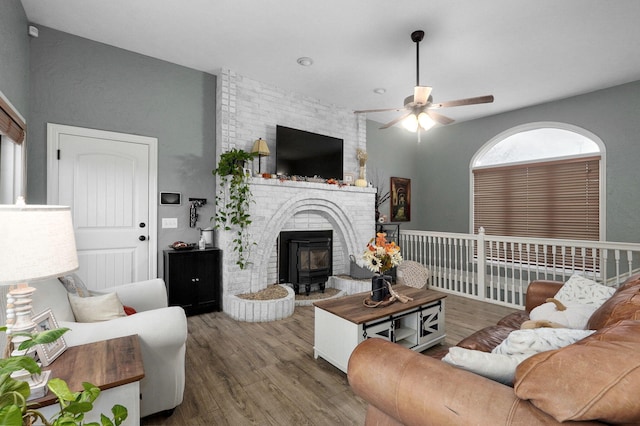 living room with hardwood / wood-style floors, ceiling fan, and a wood stove