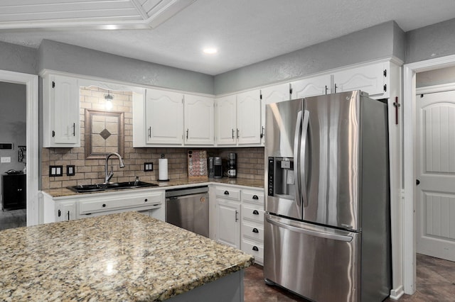 kitchen featuring light stone counters, stainless steel appliances, decorative backsplash, sink, and white cabinets