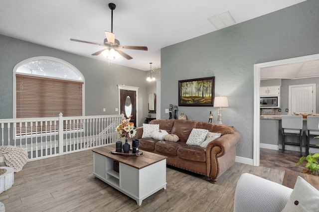 living room with ceiling fan with notable chandelier and light hardwood / wood-style flooring