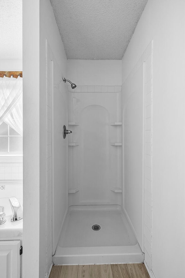 bathroom with walk in shower, wood-type flooring, and a textured ceiling