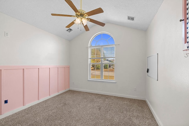 carpeted empty room with vaulted ceiling, ceiling fan, and a textured ceiling