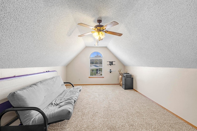 living area with carpet floors, a textured ceiling, lofted ceiling, and ceiling fan