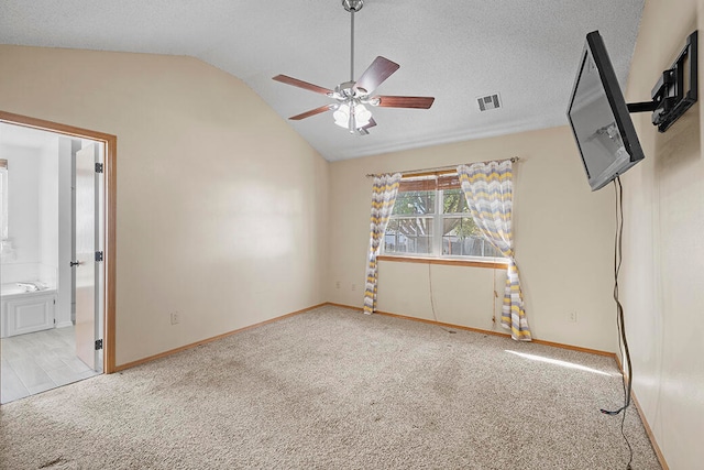 interior space featuring a textured ceiling, lofted ceiling, ceiling fan, and light carpet