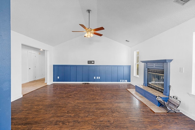 unfurnished living room with ceiling fan, dark hardwood / wood-style flooring, a tiled fireplace, and lofted ceiling