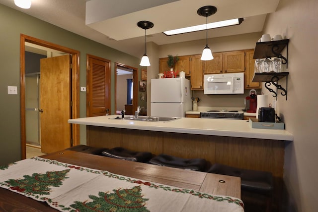 kitchen with sink, kitchen peninsula, a kitchen bar, white appliances, and pendant lighting