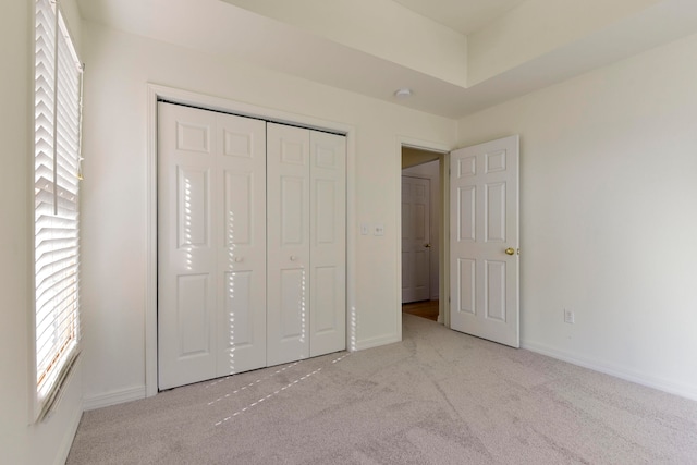 unfurnished bedroom with light colored carpet and a closet