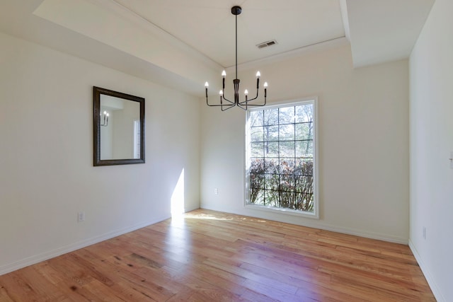 spare room with light wood-type flooring and a chandelier