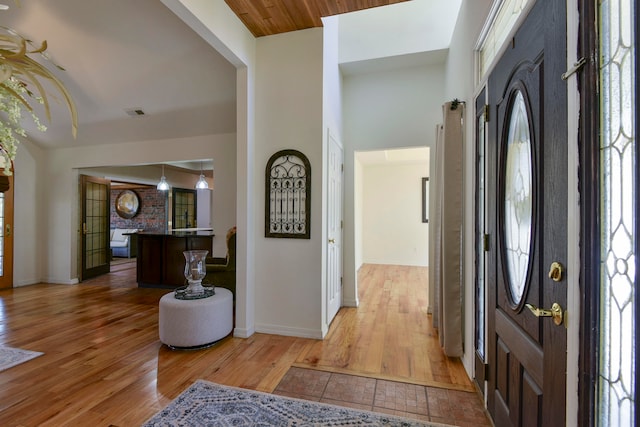 foyer with wood-type flooring, a healthy amount of sunlight, and wooden ceiling