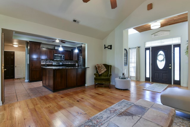 kitchen with stainless steel appliances, dark brown cabinets, decorative backsplash, sink, and light hardwood / wood-style flooring