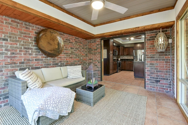 tiled living room with wooden ceiling, ceiling fan, and brick wall