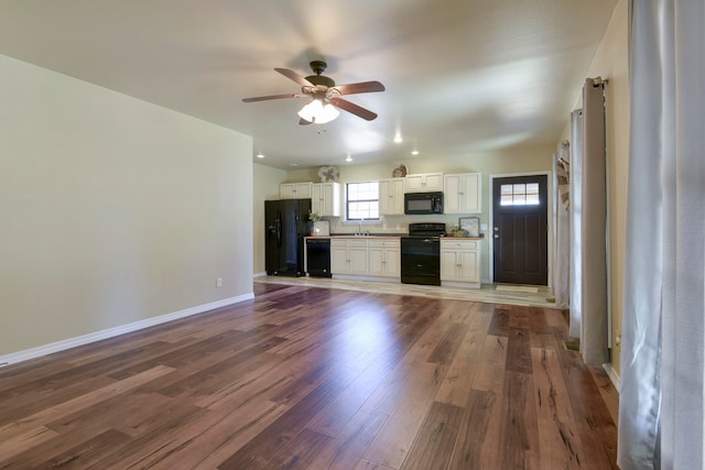 unfurnished living room featuring dark wood-type flooring, sink, and ceiling fan