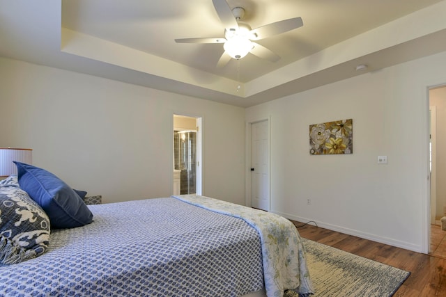 bedroom featuring ensuite bathroom, ceiling fan, dark hardwood / wood-style floors, and a tray ceiling