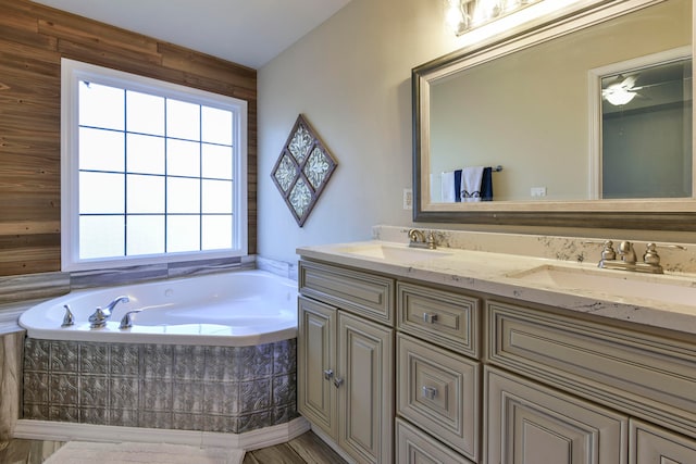 bathroom with a tub, ceiling fan, vanity, and wooden walls