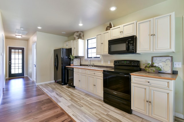 kitchen featuring a healthy amount of sunlight, black appliances, and light hardwood / wood-style flooring