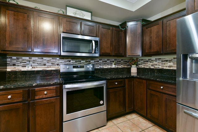 kitchen featuring dark stone countertops, backsplash, appliances with stainless steel finishes, and dark brown cabinets