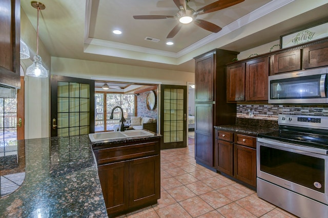 kitchen featuring stainless steel appliances, sink, tasteful backsplash, a tray ceiling, and decorative light fixtures