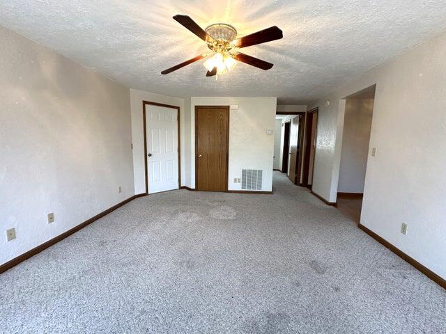 unfurnished bedroom with a textured ceiling, ceiling fan, and carpet floors