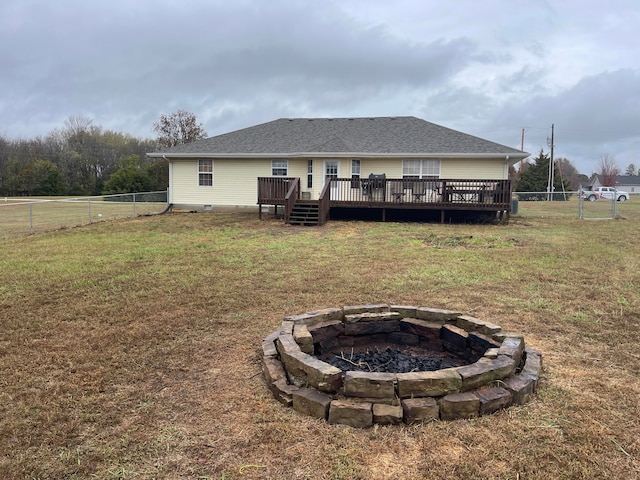 back of house featuring a lawn, a wooden deck, and a fire pit