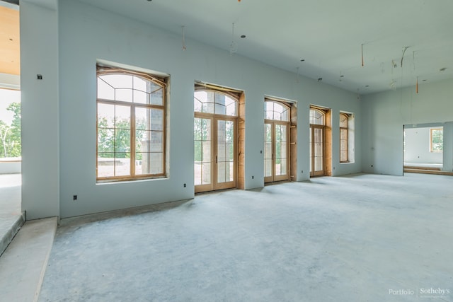 spare room featuring concrete flooring, a wealth of natural light, and french doors