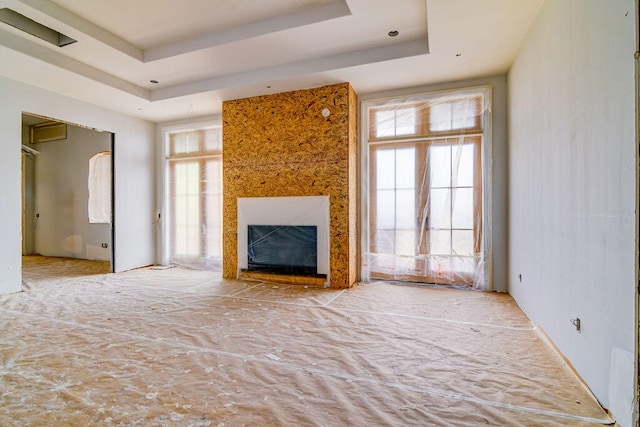 unfurnished living room with a wealth of natural light and a tray ceiling