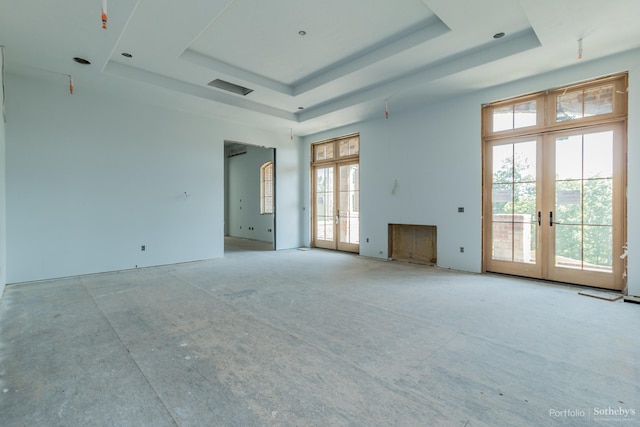 unfurnished living room with french doors and a raised ceiling