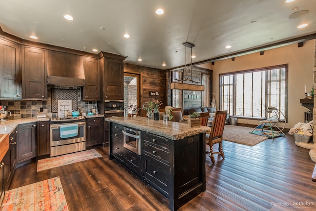 kitchen with dark wood-type flooring, hanging light fixtures, appliances with stainless steel finishes, and a center island