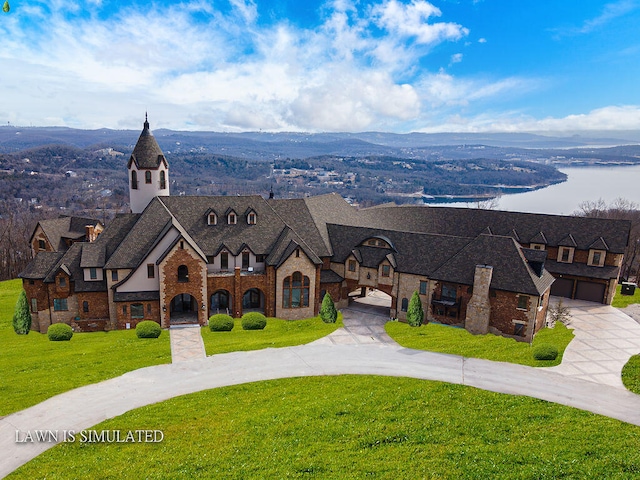 view of front of house featuring a water and mountain view, a front yard, and a garage