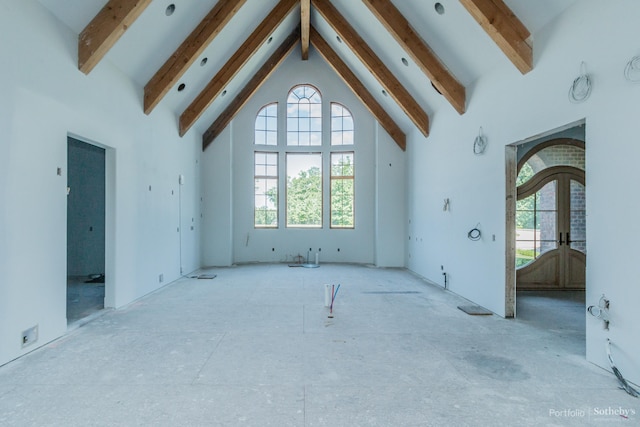 unfurnished living room with high vaulted ceiling, plenty of natural light, and beamed ceiling