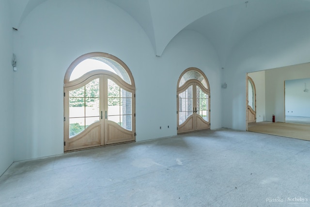 unfurnished room with high vaulted ceiling and french doors