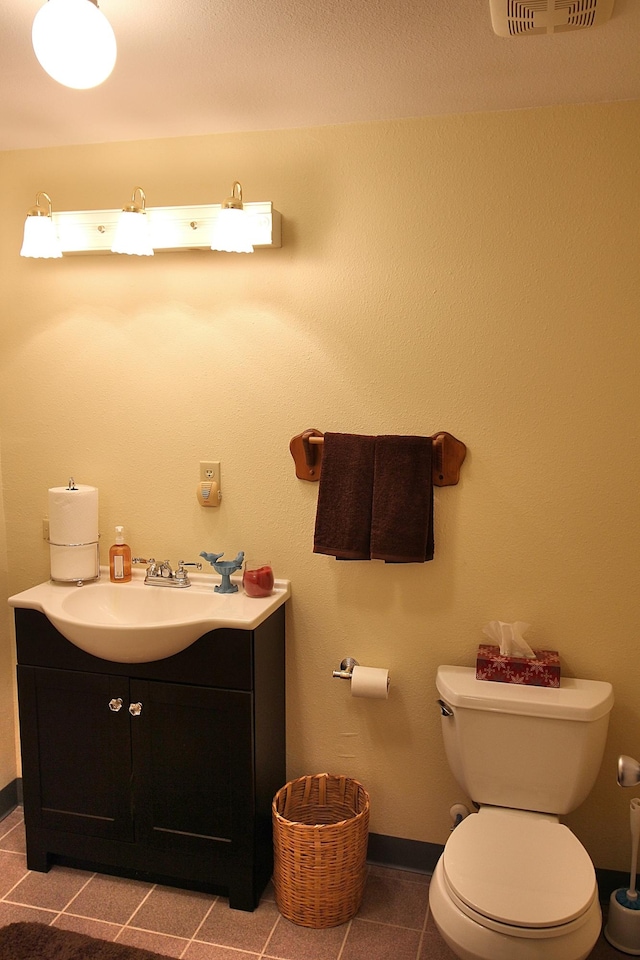 bathroom with toilet, vanity, and tile patterned flooring