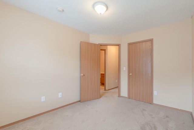 unfurnished bedroom featuring light colored carpet and a closet