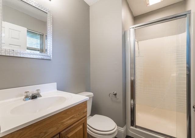 bathroom with toilet, vanity, and a shower with shower door