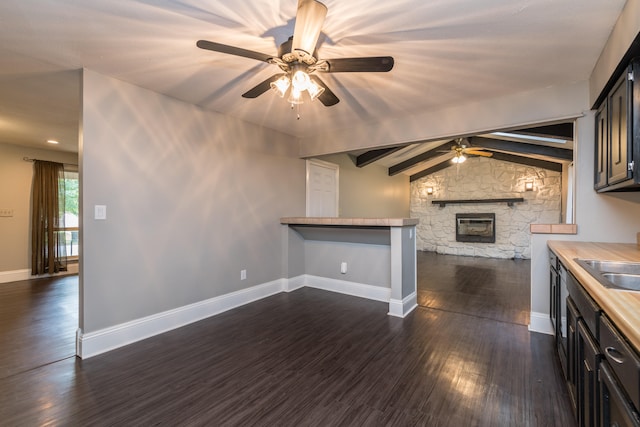 kitchen with butcher block counters, kitchen peninsula, ceiling fan, dark hardwood / wood-style floors, and vaulted ceiling with beams