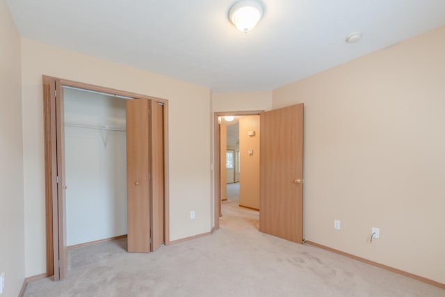 unfurnished bedroom featuring light carpet and a closet