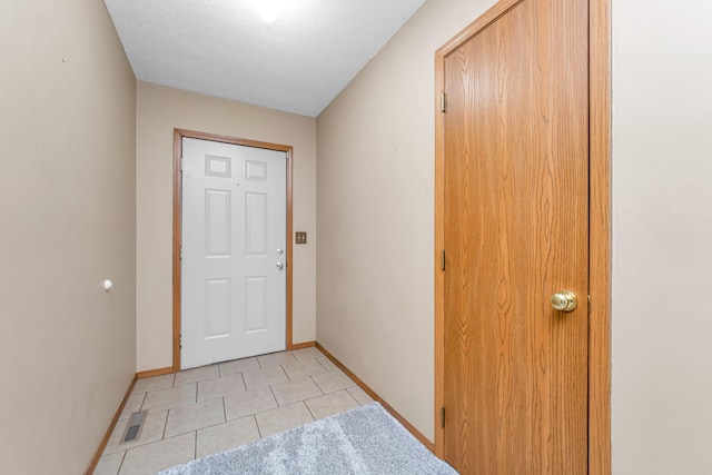 entryway with a textured ceiling and light tile patterned floors