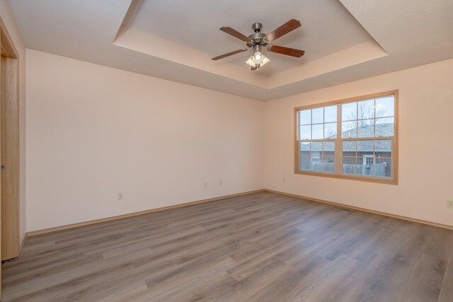 spare room with hardwood / wood-style flooring, ceiling fan, and a raised ceiling