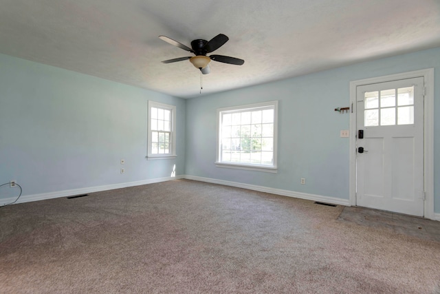 foyer with ceiling fan and carpet flooring