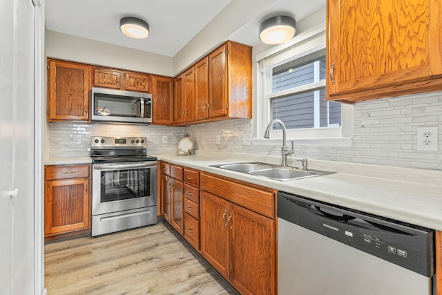 kitchen featuring light hardwood / wood-style floors, stainless steel appliances, sink, and tasteful backsplash